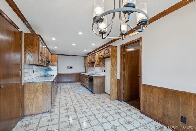 kitchen with black appliances, sink, crown molding, light stone countertops, and a chandelier