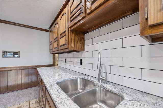 kitchen featuring a textured ceiling, crown molding, light stone countertops, and sink