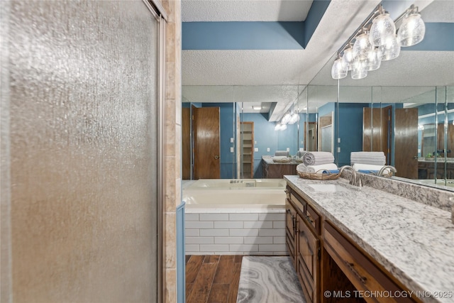 bathroom with a textured ceiling, vanity, and independent shower and bath