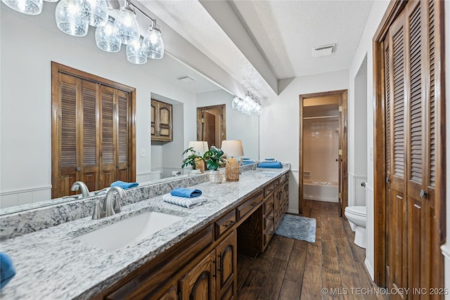 full bathroom with shower / bath combination, vanity, a textured ceiling, hardwood / wood-style floors, and toilet