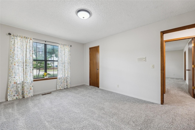 empty room featuring a textured ceiling and light carpet