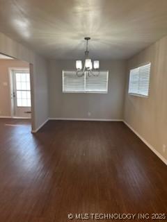 spare room with dark hardwood / wood-style flooring and a chandelier