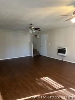 unfurnished room with ceiling fan, dark wood-type flooring, and heating unit