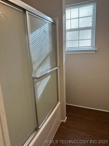 bathroom with hardwood / wood-style floors and bath / shower combo with glass door