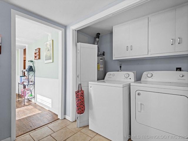 washroom featuring cabinets, light tile patterned floors, electric water heater, and washer and clothes dryer