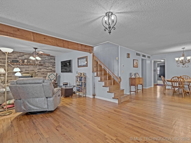 living room with a textured ceiling, light hardwood / wood-style flooring, and ceiling fan with notable chandelier