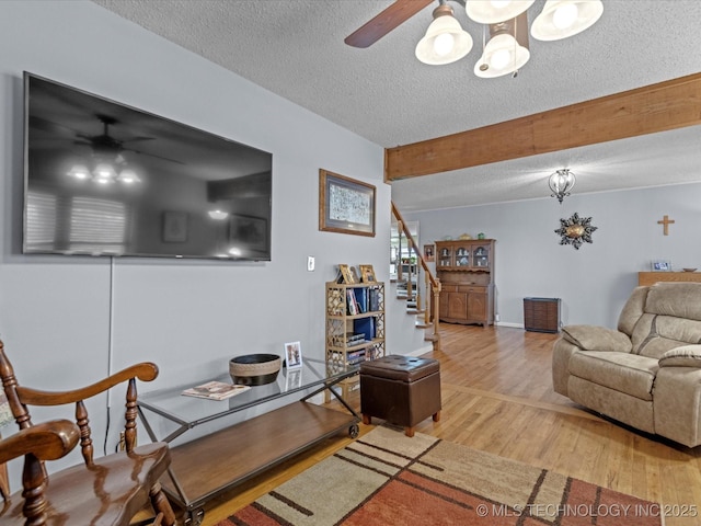 living room with hardwood / wood-style flooring, ceiling fan with notable chandelier, and a textured ceiling