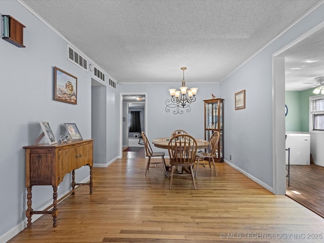 dining area with a textured ceiling, crown molding, ceiling fan with notable chandelier, and light wood-type flooring