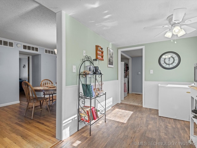 interior space featuring ceiling fan, wood-type flooring, and a textured ceiling