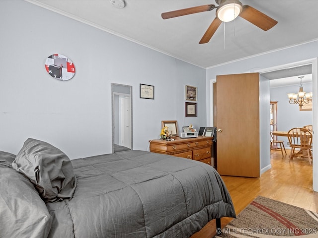 bedroom featuring hardwood / wood-style floors, ceiling fan with notable chandelier, and ornamental molding