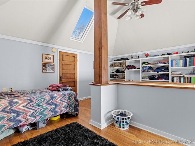 bedroom with hardwood / wood-style flooring, ceiling fan, ornamental molding, and vaulted ceiling with skylight