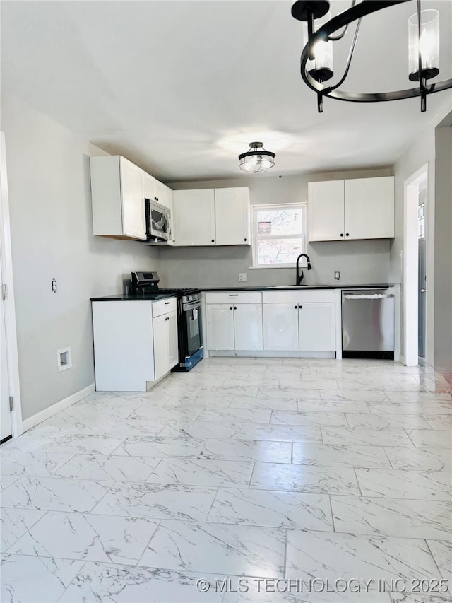 kitchen featuring pendant lighting, white cabinets, sink, appliances with stainless steel finishes, and a notable chandelier