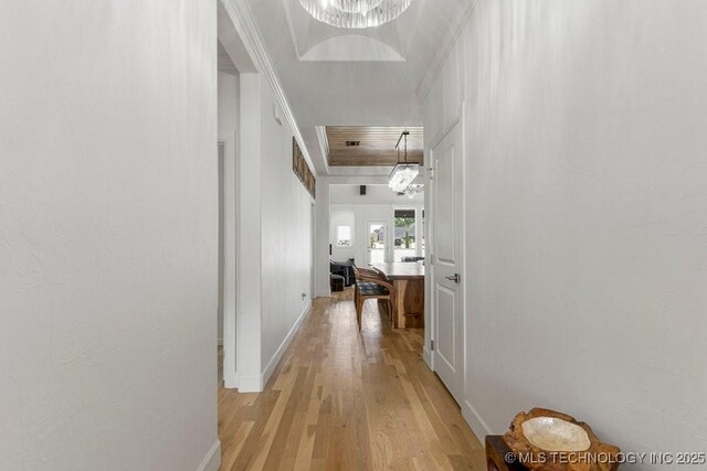 corridor with a chandelier, light hardwood / wood-style floors, and ornamental molding