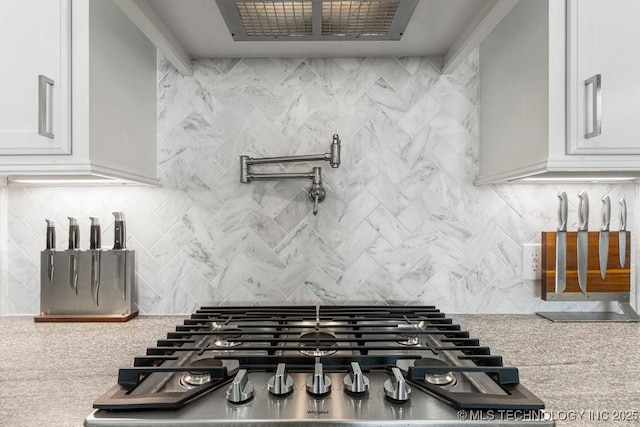 kitchen with stainless steel gas stovetop and white cabinetry