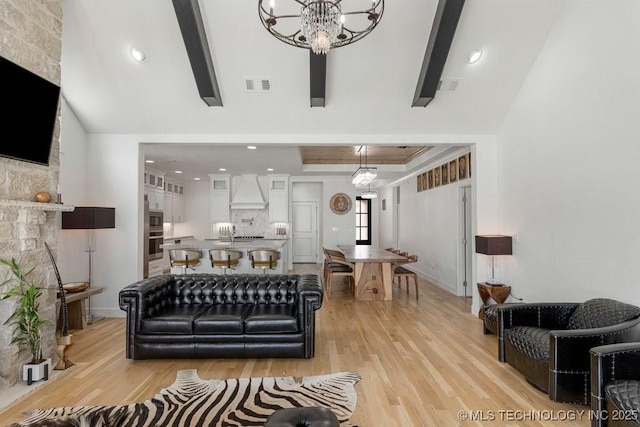 living room with a chandelier, beam ceiling, and light hardwood / wood-style floors