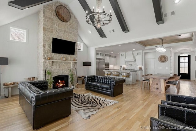 living room with high vaulted ceiling, light hardwood / wood-style flooring, a fireplace, beam ceiling, and a chandelier