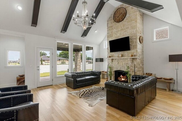 living room with a fireplace, beam ceiling, light wood-type flooring, and a chandelier