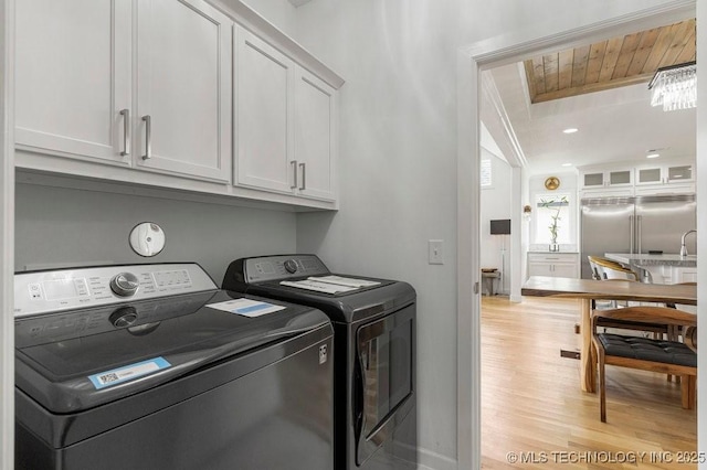 laundry room with cabinets, independent washer and dryer, and light wood-type flooring