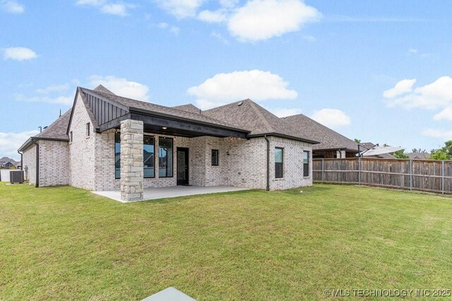 rear view of house featuring central air condition unit, a patio area, and a yard