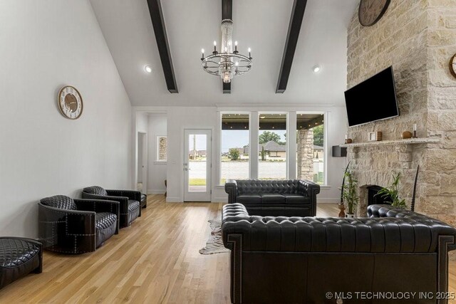 living room featuring a stone fireplace, lofted ceiling with beams, light hardwood / wood-style flooring, and a chandelier