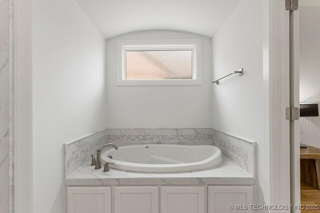 bathroom with a bathing tub and vaulted ceiling