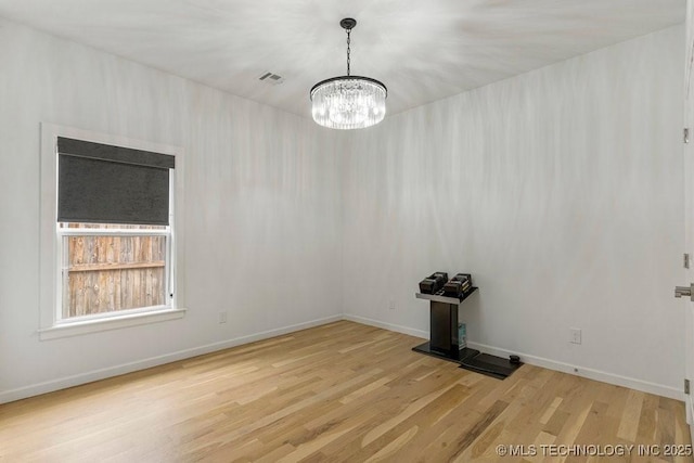 spare room featuring light hardwood / wood-style floors and an inviting chandelier