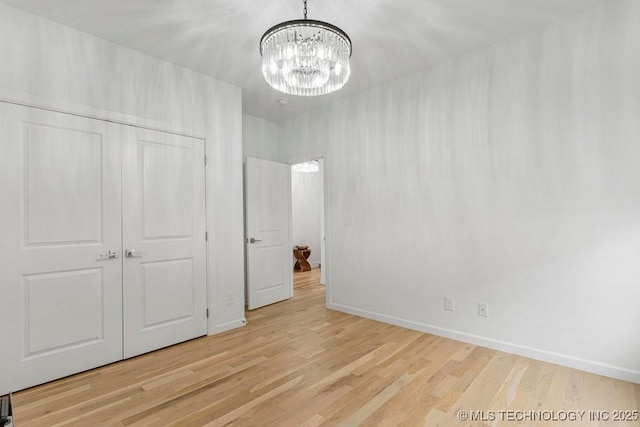 unfurnished bedroom featuring a closet, light wood-type flooring, and an inviting chandelier