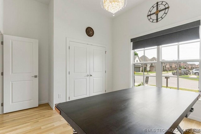 interior space with a chandelier, a towering ceiling, and light hardwood / wood-style floors