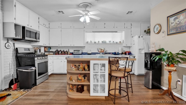 kitchen with white cabinetry, a center island, ceiling fan, a kitchen breakfast bar, and appliances with stainless steel finishes