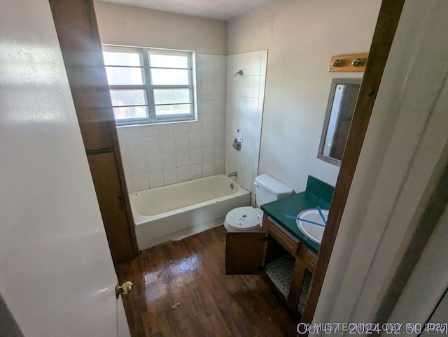 full bathroom featuring hardwood / wood-style flooring, tiled shower / bath combo, toilet, and vanity