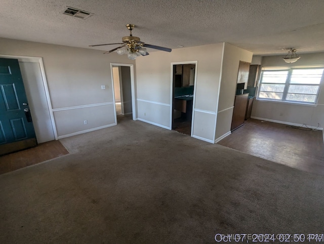 interior space with ceiling fan, dark carpet, and a textured ceiling