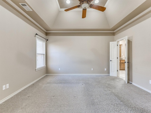 carpeted empty room featuring a raised ceiling, vaulted ceiling, ceiling fan, and crown molding