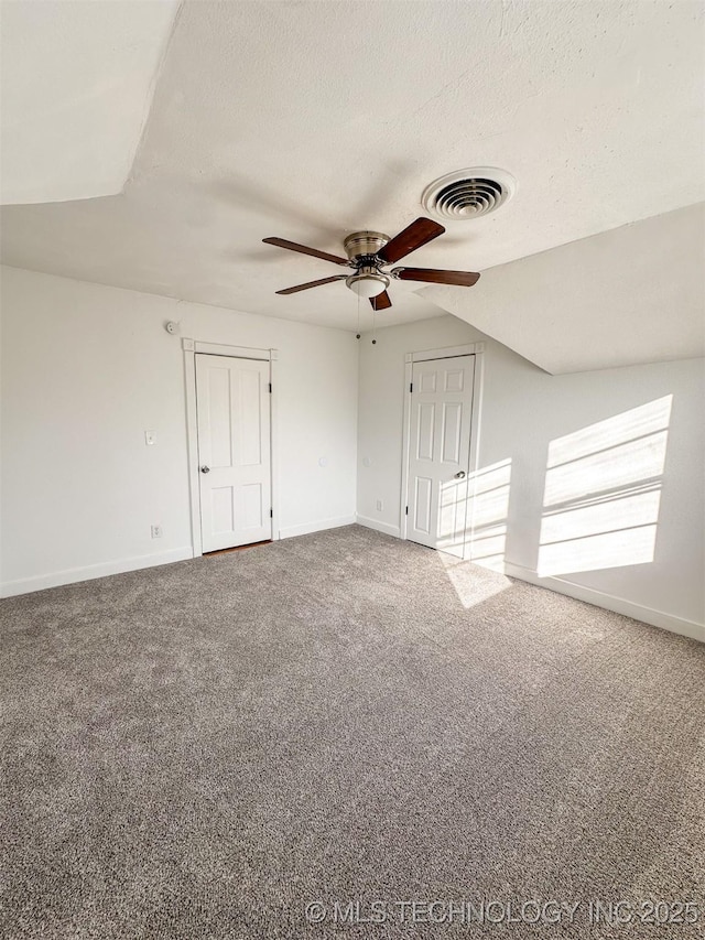 empty room featuring a textured ceiling, ceiling fan, carpet, and vaulted ceiling