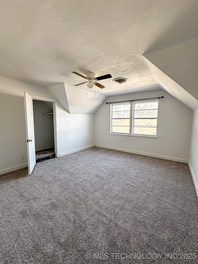 additional living space featuring carpet flooring, ceiling fan, a textured ceiling, and vaulted ceiling