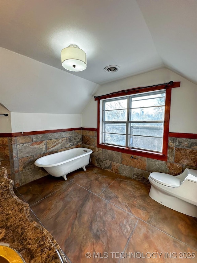 bathroom with a bath, toilet, and lofted ceiling