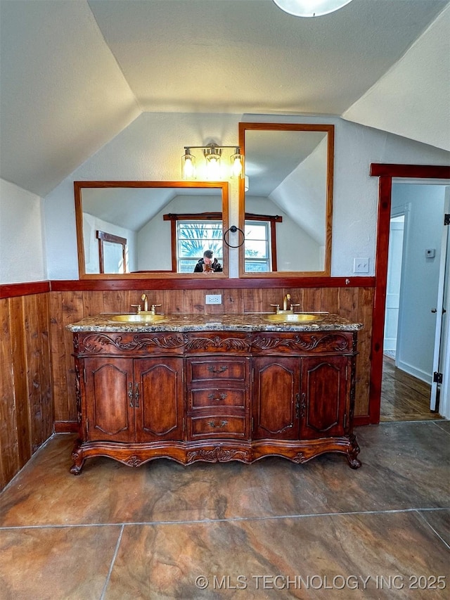 bathroom featuring vanity, wood walls, and vaulted ceiling