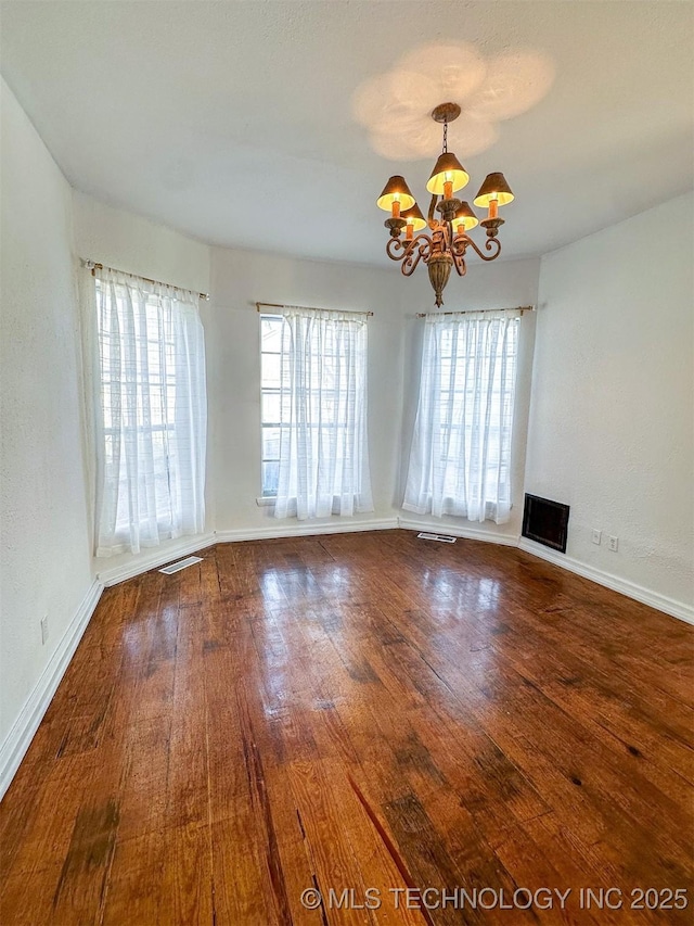 unfurnished room with a chandelier and wood-type flooring