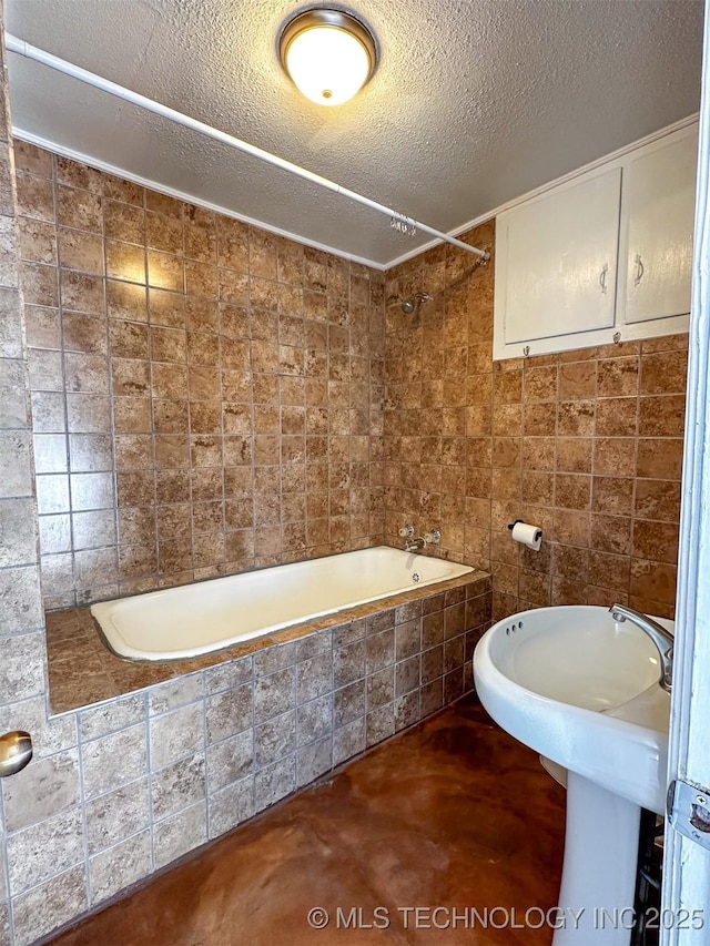 bathroom featuring a textured ceiling and tiled shower / bath combo