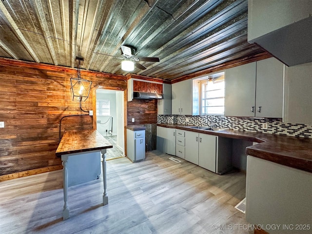 kitchen with backsplash, wood ceiling, sink, pendant lighting, and butcher block countertops