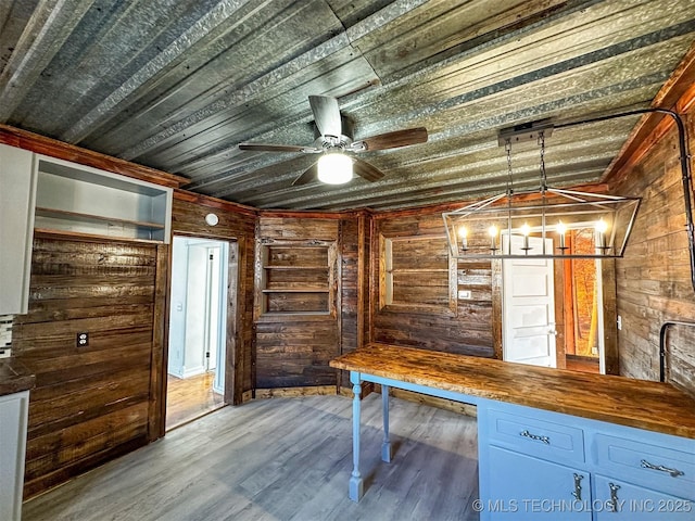 interior space featuring hardwood / wood-style floors, ceiling fan with notable chandelier, wood walls, and wooden ceiling