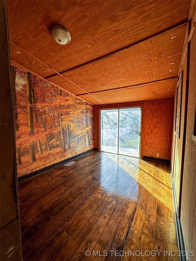 unfurnished living room featuring wood-type flooring, wood ceiling, and wooden walls