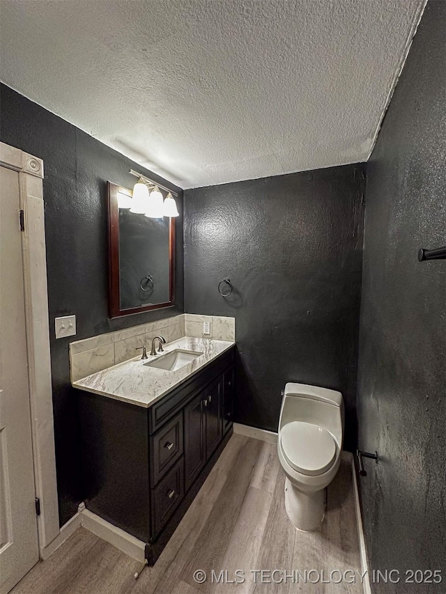 bathroom with toilet, vanity, a textured ceiling, and hardwood / wood-style flooring