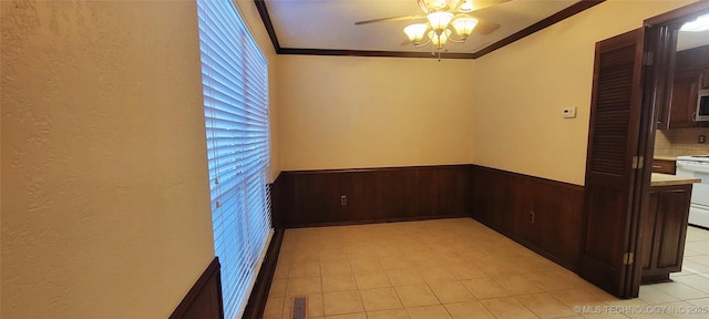 spare room featuring ceiling fan, ornamental molding, and wooden walls