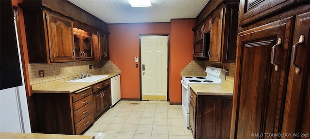 kitchen featuring backsplash, dark brown cabinets, a textured ceiling, white appliances, and sink