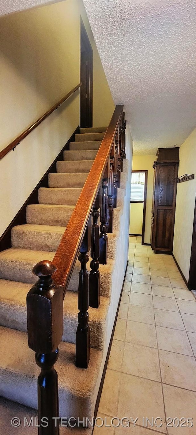 stairway featuring tile patterned flooring and a textured ceiling