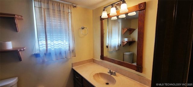 bathroom with vanity, toilet, and a textured ceiling