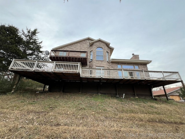 back of house featuring a lawn and a deck