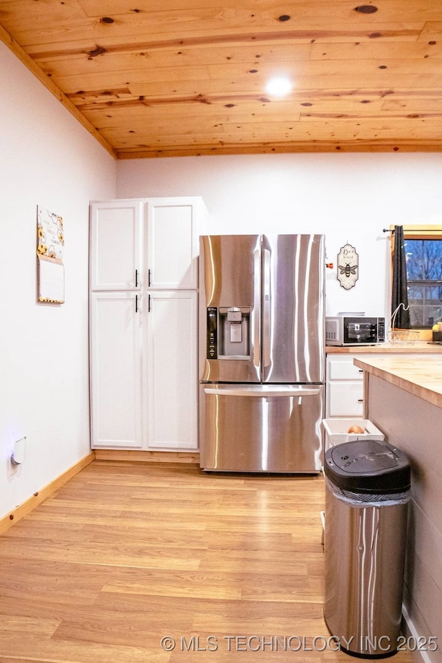 kitchen with stainless steel fridge, light wood-type flooring, wooden ceiling, butcher block countertops, and white cabinetry