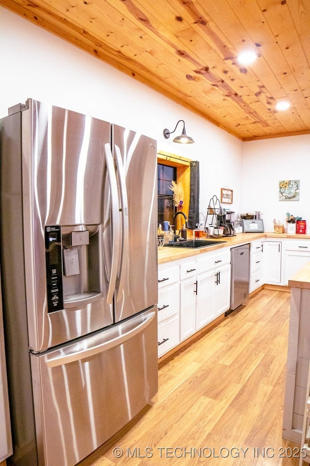 kitchen with stainless steel appliances, sink, wooden ceiling, white cabinets, and butcher block counters