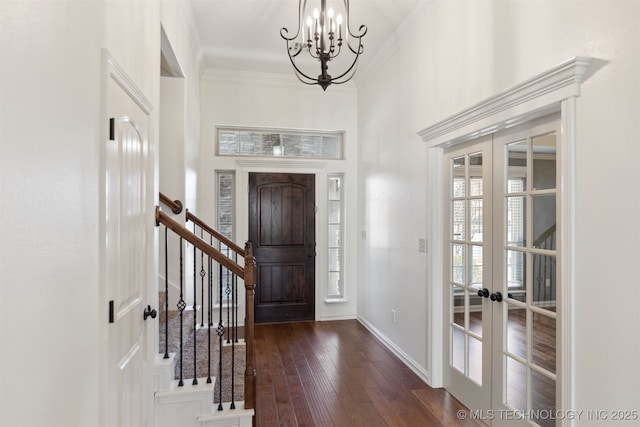 foyer featuring dark hardwood / wood-style flooring, french doors, ornamental molding, and a notable chandelier